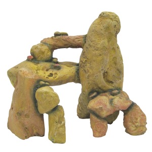 Colorful, weathered rock sculpture with an arch and hollowed openings, yellow-green with pink highlights.