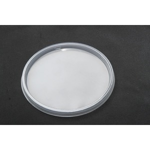 Round clear Petri dish containing a white powdery substance on a dark surface.