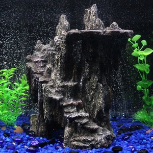 Rocky aquarium centerpiece with stepped cliff, blue gravel, and bright green plants.