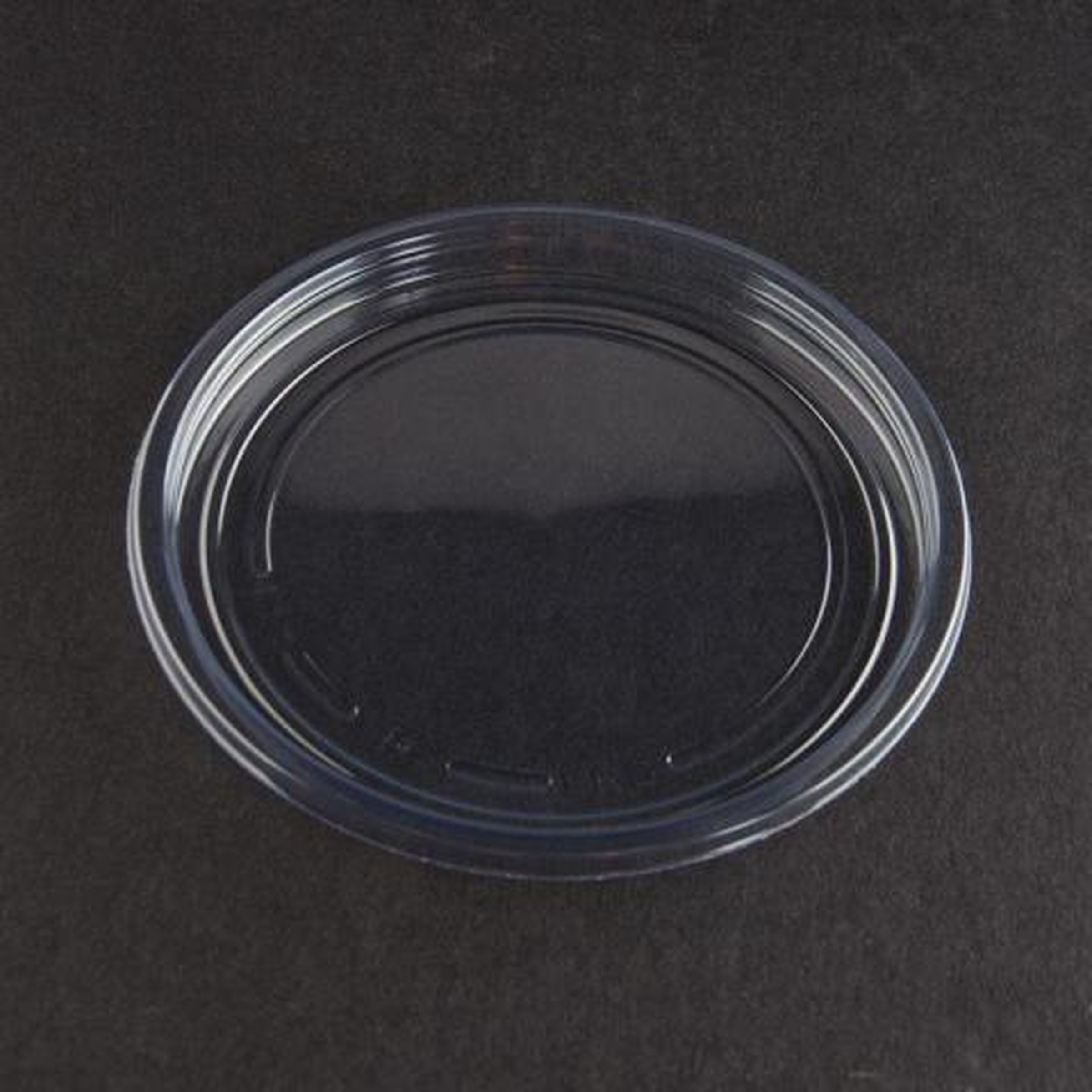clear round plastic lid on a dark surface, top view