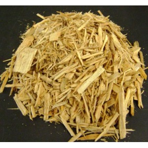 A mound of light wood shavings scattered on a dark surface.