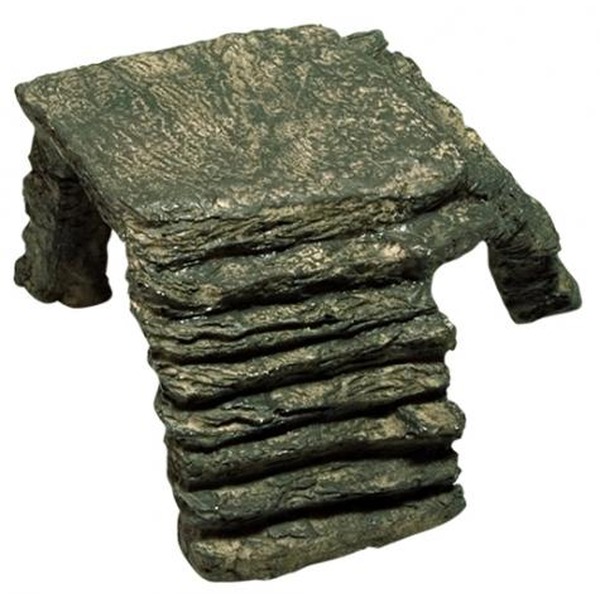 Rough, layered rock sculpture resembling a small chair with stone arms and a flat seat.