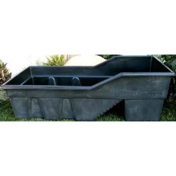 Grey plastic stock tank on a lawn, a large rectangular tub with an opening on one side.