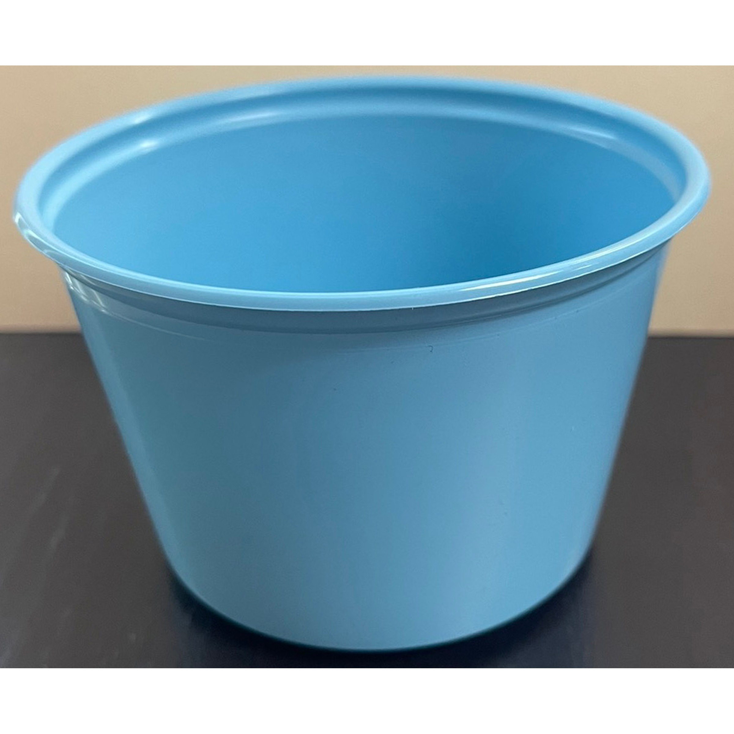 Blue plastic bucket with open top sits on a dark surface, viewed from above