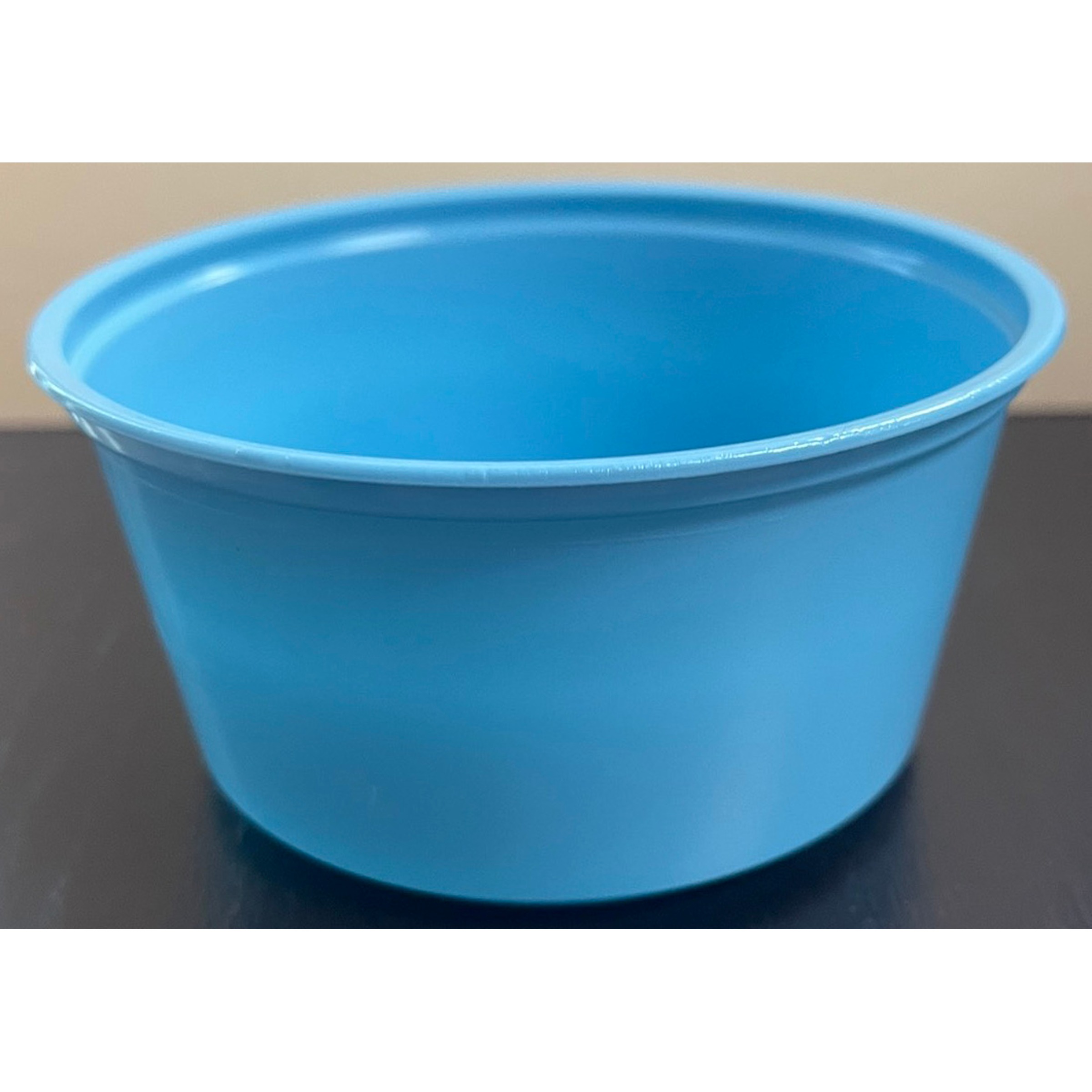 Blue plastic bucket on a dark surface, empty.