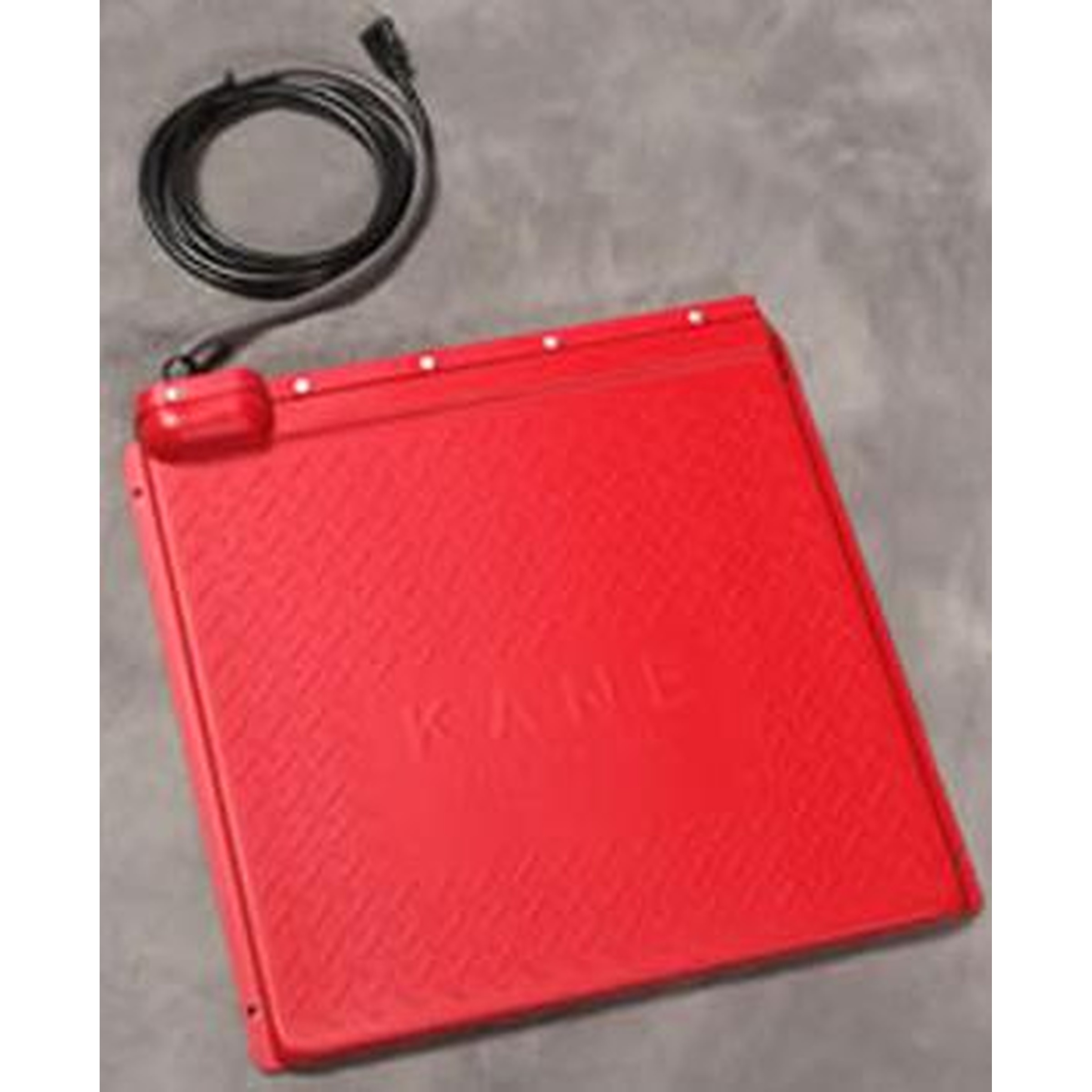 Red square electronic device with a textured surface and a coiled black cable beside it.