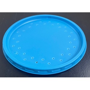 Blue circular lid with numerous small holes arranged around the edge, resting on a dark surface.