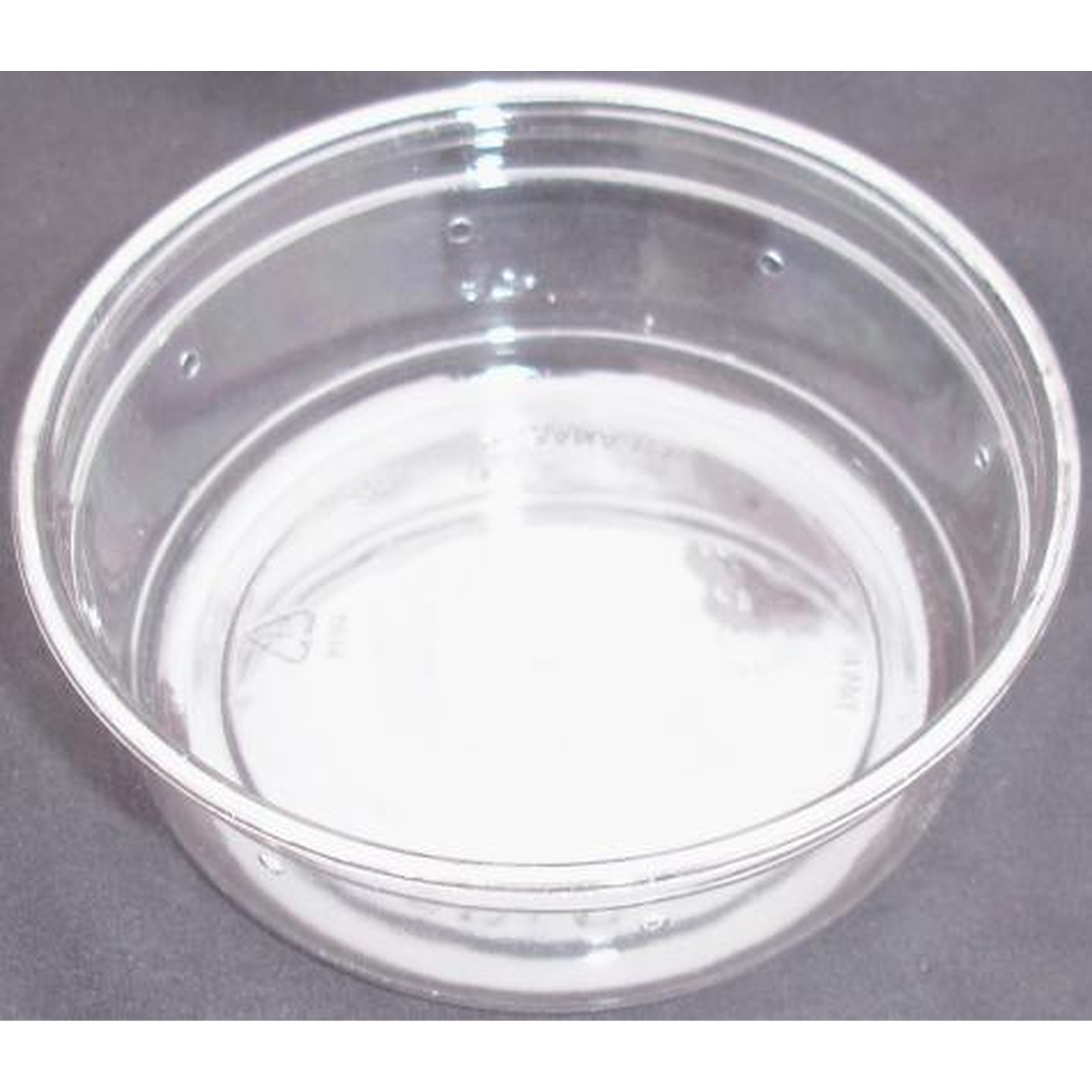 Clear glass bowl on a gray surface, empty with reflections and light highlights.