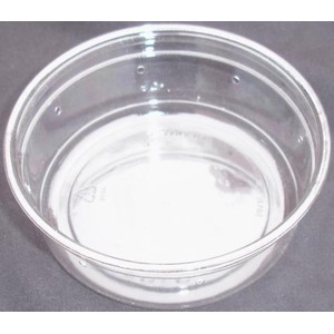 Clear glass bowl on a gray surface, empty with reflections and light highlights.